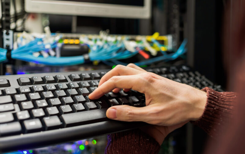 Man data center technician performing server maintenance. Using keyboard to configure infrastructure